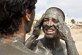 Tourists smearing mud on the banks of the Dead Sea Jordan