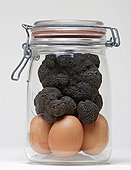 Black truffles and eggs in a jar on white background 