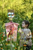 Girl installing a scarecrow in a kitchen garden France ; Age: 4 years