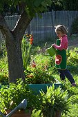 Little girl watering flowers in a garden