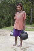 Girl returning from a source Papua New Guinea  ; She wears a bag on his head called Biloum