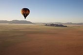 NamibRand Nature Reserve ; Namibia - The hot-air balloon above a sandy plain at the edge of the Namib Desert. In March during the rainy season with a delicate carpet of green desert grass. NamibRand Nature Reserve, Namibia.