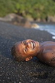 Child lying on black sand - Tanna Island Vanuatu 