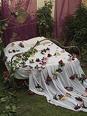 Romantic style bed with bedsheets and rose petals in exhibit