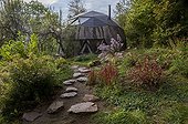 Japanese path and geodesic shaped house in a flowered garden