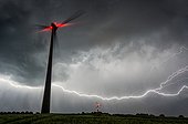 Lightning in clouds and windmill in the evening - France 