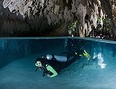 Diver in the Cenote Pet Cemetery - Yucatan Mexico ; scuba diver begins a cenote dive, having entered the water through a hole in the jungle floor. This underground chamber leads to passageways and rooms spectacularly decorated with limestone formations.