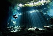 Scuba Divers in the Kukulkan Cenote - Yucatan Mexico ; scuba divers swim into a curtain of light shining down through the opening to a cenote, the entranceway to caverns and tunnels waiting to be explored