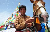 Rider praying before the race when Lapsté - Tibet China  ; Equestrian Festival Lapste <br>Before racing, the riders and their horses are praying gods by turning around a stupa and throwing sacred papers in the air.