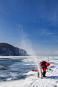 Cutting a hole in the ice before a dive - Lake Baikal, Siberia, Russia