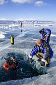 Diver in a hole cut in ice, Lake Baikal, Siberia, Russia