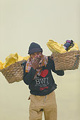 Indonesia, Java Island, East Java province, Kawah Ijen volcano, Miner carrying baskets of sulfur