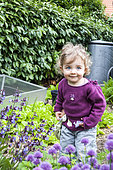 Little girl and Chive in bloom in a garden
