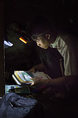 Lagaï, 13, preparing his satchel with a flashlight, Pulau Siberut, Sumatra, Indonesia