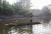Women going to go fishing on their dugout made in a tree Meranti (Shorea sp.) at dawn, Pulau Siberut, Sumatra, Indonesia