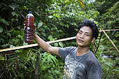 Patchouli oil producer showing a bottle full of patchouli oil, Pulau Siberut, Sumatra, Indonesia