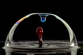 Drops of colored water and soap bubble on black background