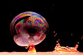 Drop of colored water and soap bubble on black background