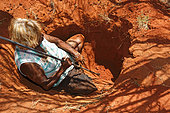 The Honey Ants Dream. Audrey Martin, a 59-year-old Aborigine woman digging with a burrowing stick, these days made of metal. Once made of acacia aneura wood, this stick was also used as much to dig up honey ants and tubers as to throw at prey such as lizards and other small animals. Northern Territory, Australia