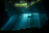 Scuba diver explores a cave in rays of light, Yucatan Peninsula, Mexico