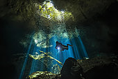 Scuba diver explores a cave in rays of light, Yucatan Peninsula, Mexico