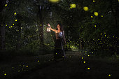 A girl is looking for the fireflies on a forest near the Po river in Italy