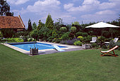 Garden with swimming pool and sitting area with lounge chair in summer, Belgium