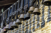 Bells of Montbéliard cows hung under the roof of a farm for decoration, Doubs, France
