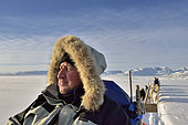 Tourist hitching sled dogs on the ice floe of Scoresbysund, Greenland
