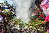 Kanak women with yams wrapped on fire. Kanak traditional oven with braising. Feast of the new yam. Tribe of Gohapin. New Caledonia.