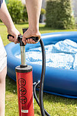 Woman inflating a freestanding pool in a garden, summer, Pas de Calais, France