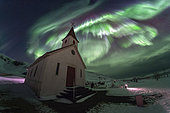 Aurora borealis and Reyniskirkja church in southern Iceland. During a strong auroral activity, an aurora borealis dances over the church of Reynis.