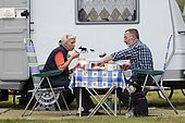 Pair with miniature Schnauzer eating at a table in front of a mobile home, Lower Saxony, Germany, Europe, Europe