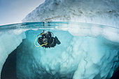 Spit image of a scuba diver diving close to an iceberg, only in springtime, when the hard winter slowly subsides, are the ice-cold waters suitable for divers who can dive around a iceberg that floats in crystal-clear water, Tasiilaq, East Greenland