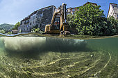 Mid-air half-water view of a digger during work to restore ecological continuity on the Lergue River, Lodève, Hérault, Occitanie region, France