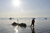 Kayaker pulling his kayak on the shoals of Scoresbysund, North East Greenland
