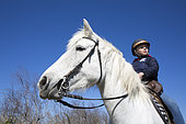 Léa, 8, rides her mare called Brume along the canals, Saintes-maries-de-la-mer, Camargue, France