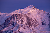 Mont-Blanc and Goûter huts lit by the Alpenglow, Haute-Savoie, France. Shot from Sallanches, in February 2020. The alpenglow is an optical phenomenon that appears after sunset. The rays of the sun are reflected by the cloud layer and give a red or pink tint to the Alpine massifs.