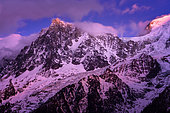 Aiguille du Midi lit by the Alpenglow. Shooting from Les Houches, in February 2020. Haute-Savoie, France. The alpenglow is an optical phenomenon that appears after sunset. The rays of the sun are reflected by the cloud layer and give a red or pink tint to the Alpine massifs.