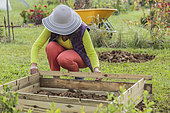 Woman setting up a prefabricated wooden kitchen garden square