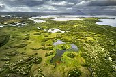Finely structured landscape with green vegetation and small lakes and islands, behind volcanic cones and clouds, volcano at Lake Mývatn, Skútustaðir, Norðurland eystra, Iceland, Europe