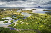 Finely structured landscape with green vegetation and small lakes and islands, behind volcanic cones and clouds, volcano at Lake Mývatn, Skútustaðir, Norðurland eystra, Iceland, Europe