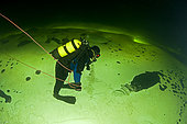 Scuba diver under ice walking upside down, exercise to practice orientation, Arctic circle Dive Center, White Sea, Karelia, northern Russia
