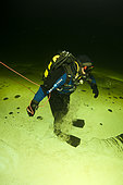 Scuba diver under ice walking upside down, exercise to practice orientation, Arctic circle Dive Center, White Sea, Karelia, northern Russia
