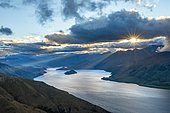Last rays of sun shining through cloudy sky, view of Lake Wanaka at sunset, lake and mountain landscape, view from Isthmus Peak, Wanaka, Otago, South Island, New Zealand, Oceania