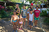 Group of people holding a young black spider monkey (Ateles paniscus) in French Guyana