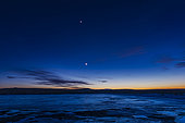 March 26, 2020 - The waxing crescent moon with earthshine and (above) Venus shine in the evening twilight sky over an icy pond in Alberta, Canada. Venus was just past greatest elongation from the Sun, and being spring with the high angle of the ecliptic, Venus was as high as it can get this year in an evening apparition. The Pleiades is at very top.
