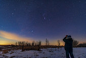 Astronomer using binoculars to view the Orion Nebula just before local moonrise on February 10, 2020.