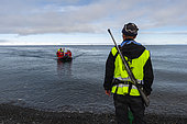 An armed guide on the shore of Mushamna awaits for cruise tourists. Spitsbergen Island, Svalbard, Norway.