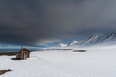 A fox hunting log cabin on the snow covered beach at Mushamna. Mushamna, Spitsbergen Island, Svalbard, Norway.